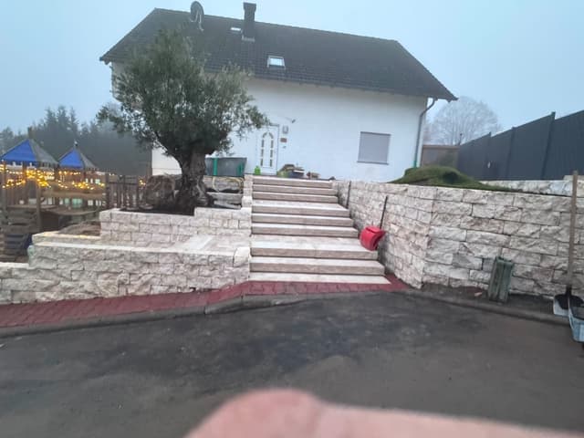 Natursteinmauer mit Außentreppe vor einem Einfamilienhaus
